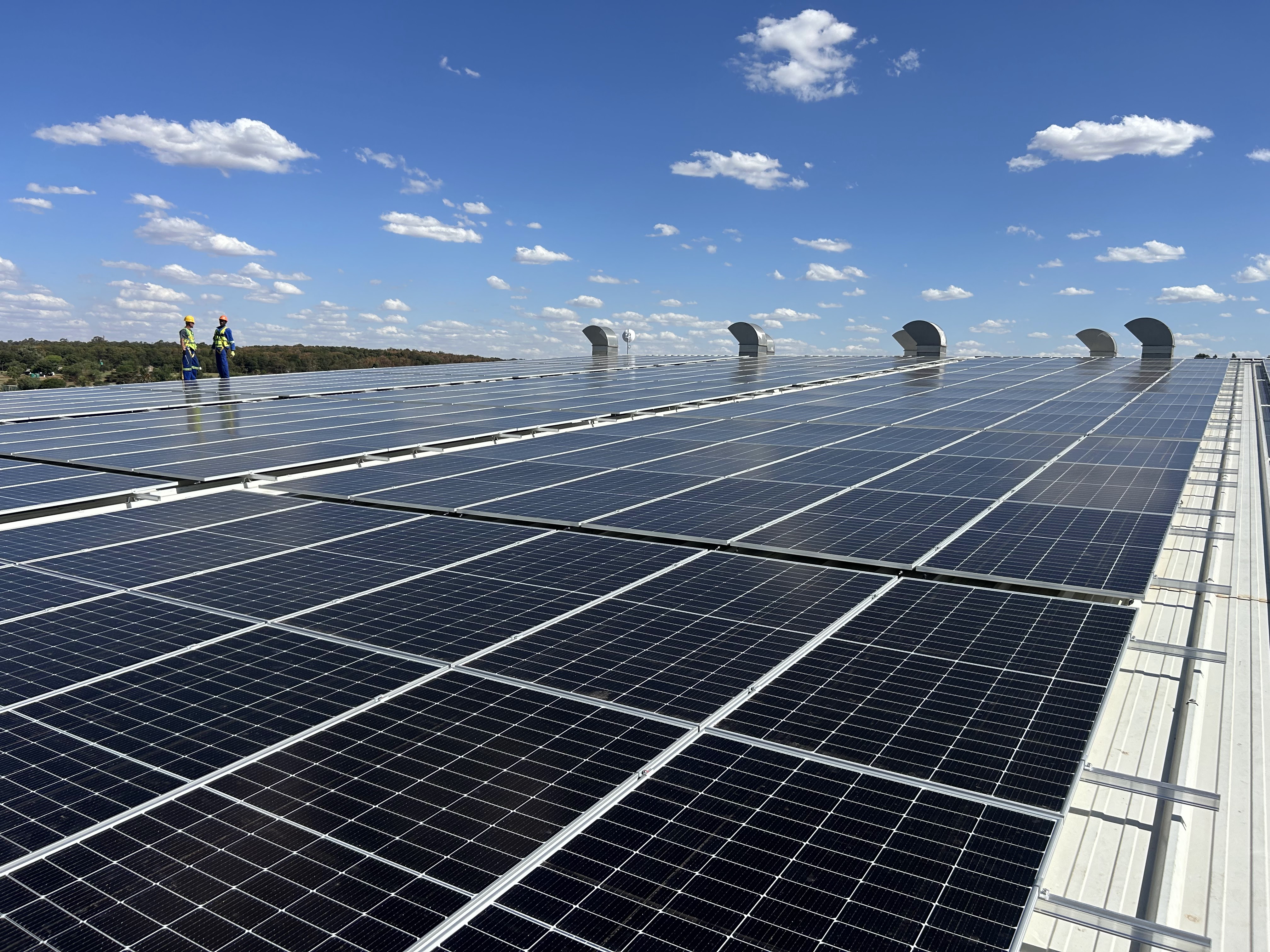 Technicians on a large-scale solar array built for a heavy-industrial and mining energy user